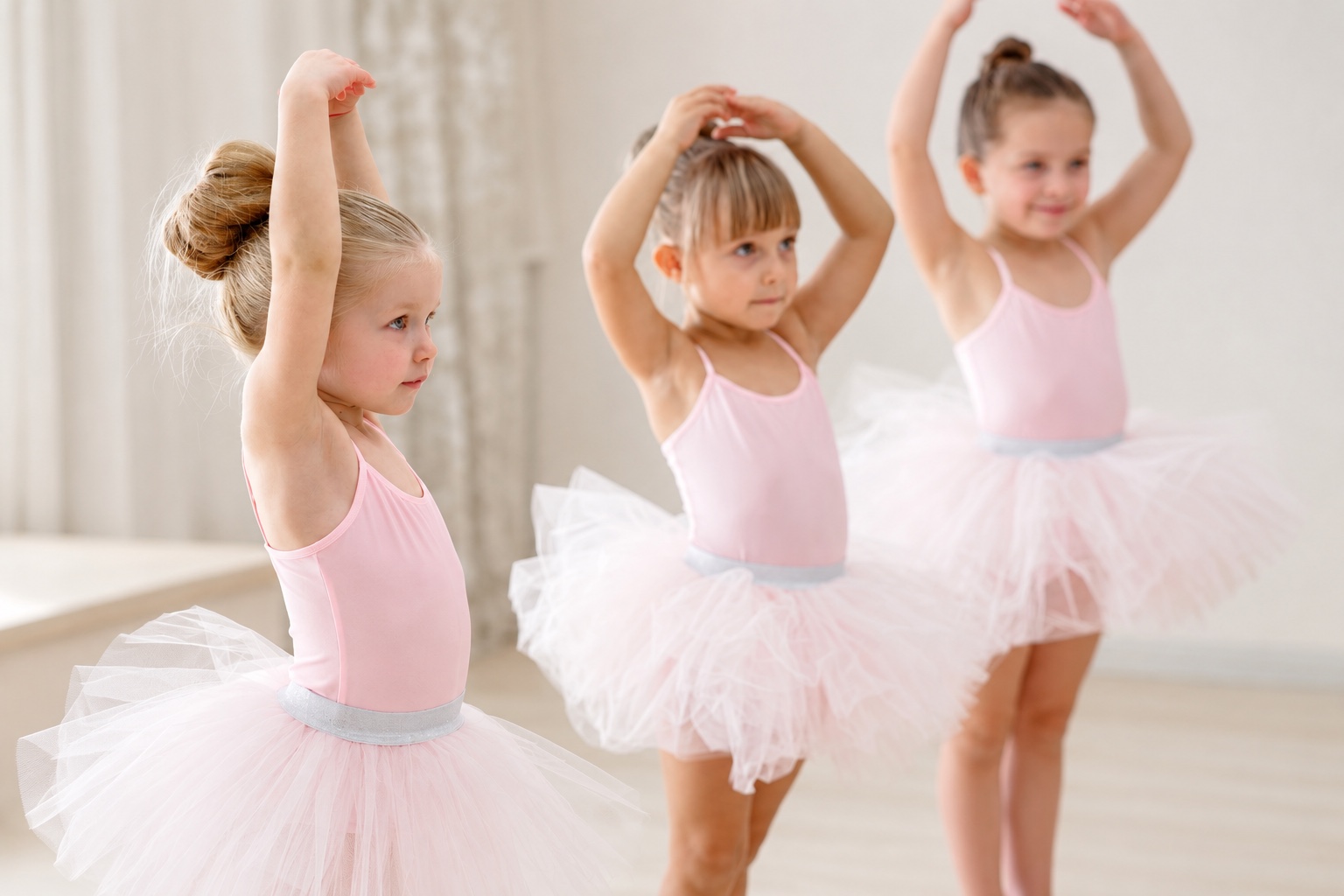 Drei Kinder in rosa Ballettkleidung üben gemeinsam Armpositionen